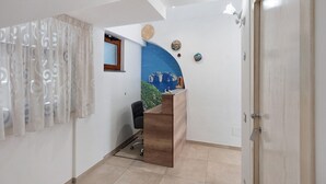 Un comptoir d’accueil avec un revêtement en bois, une chaise de bureau noire, une fenêtre avec un cadre en bois et un mur d’accent bleu.