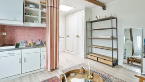 Une cuisine moderne avec des meubles blancs, un rideau rose et une étagère en bois.