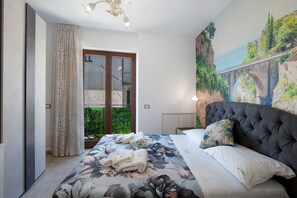 A bedroom with a bed, a large painting, and a view of a bridge and greenery. - Room 'Le 5 Perle - Furore' with Mountain View, Wi-Fi and Air Conditioning (Agerola)