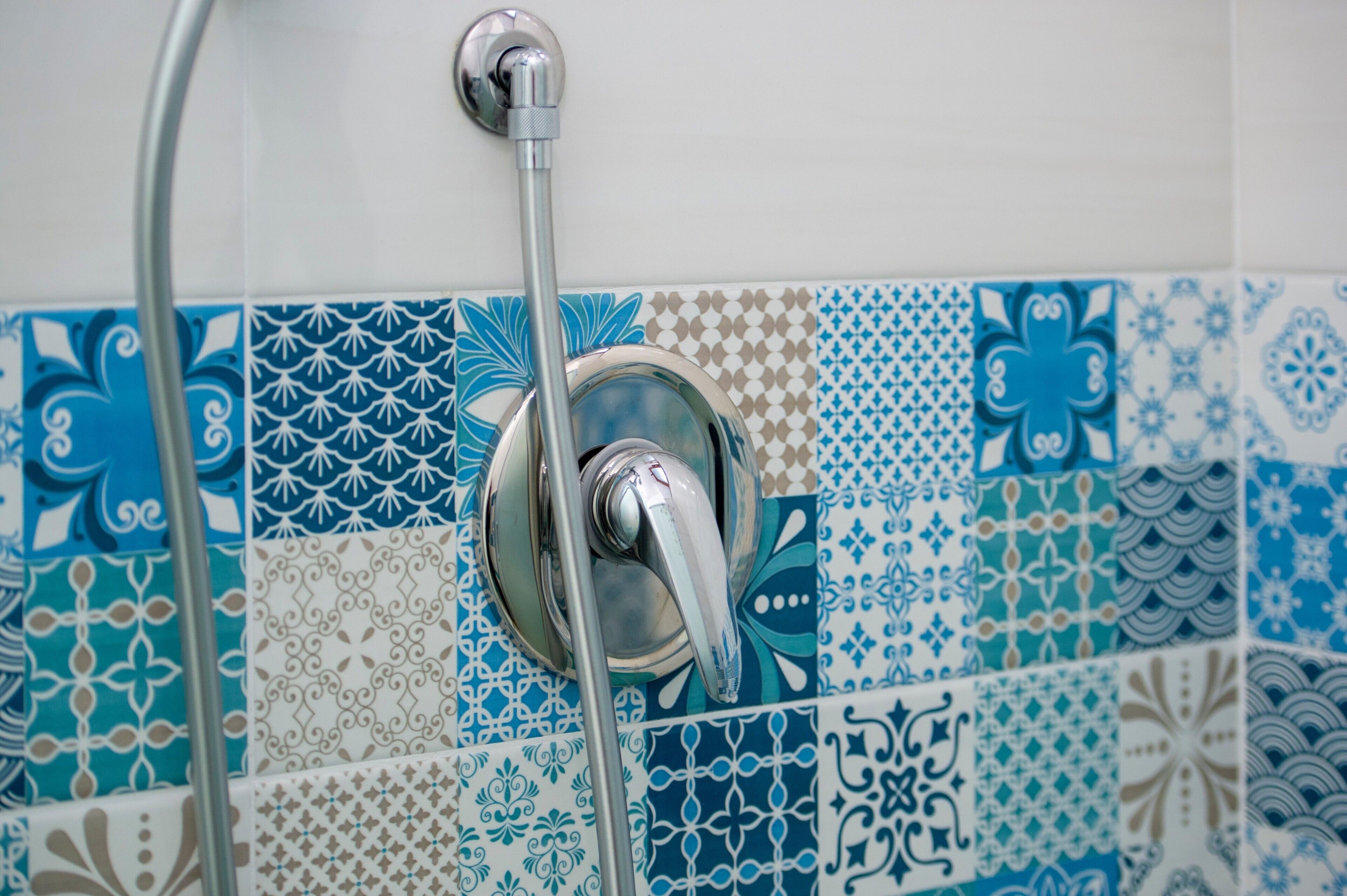 Ein Badezimmer mit Dusche und Fliesenwand mit verschiedenen geometrischen Mustern.