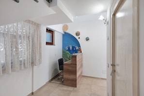 Una recepción con encimera de madera, una silla de oficina negra, un ventanal con marco de madera y una pared azul de acento.