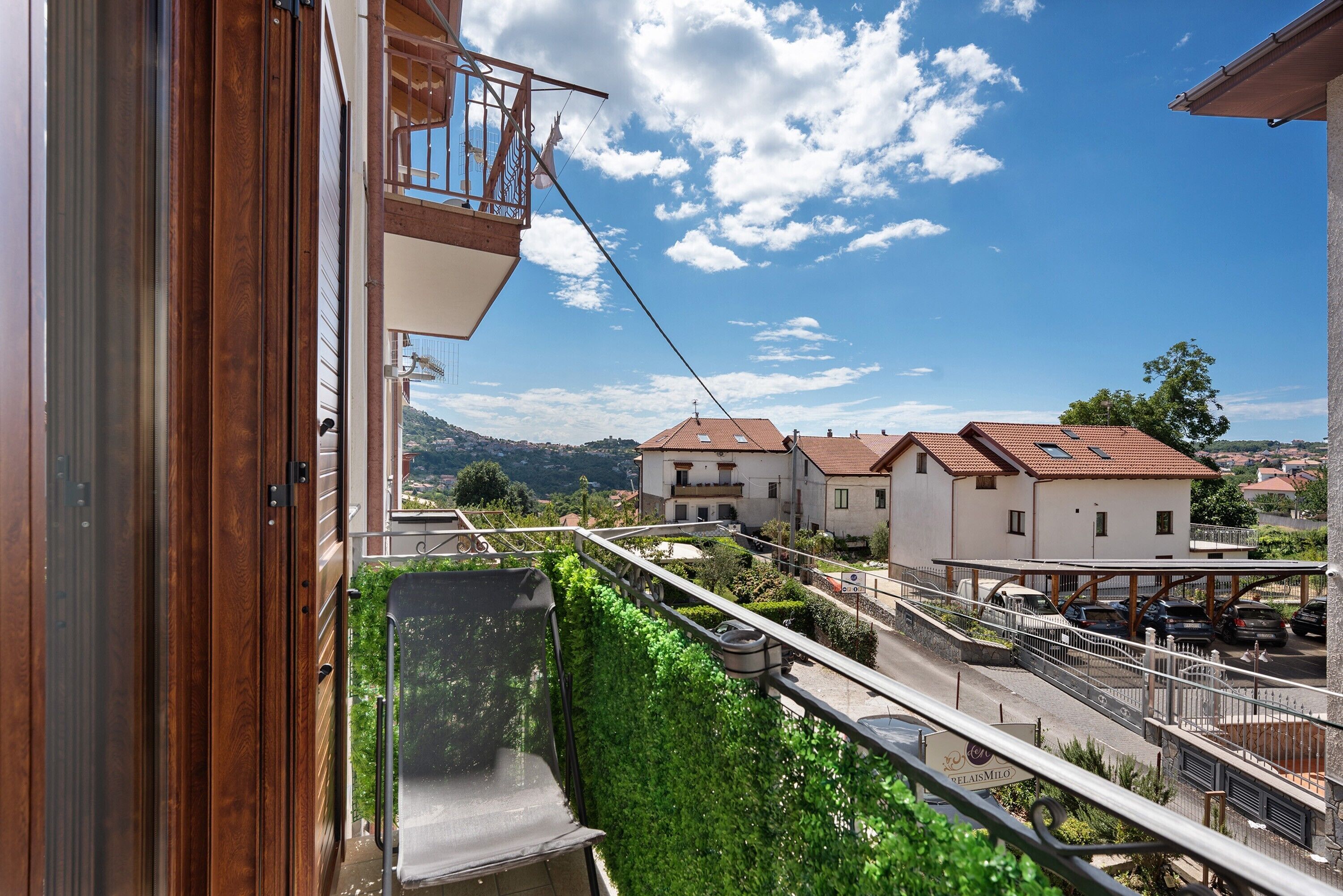A residential building with a balcony, a view of the street, and a clear sky.