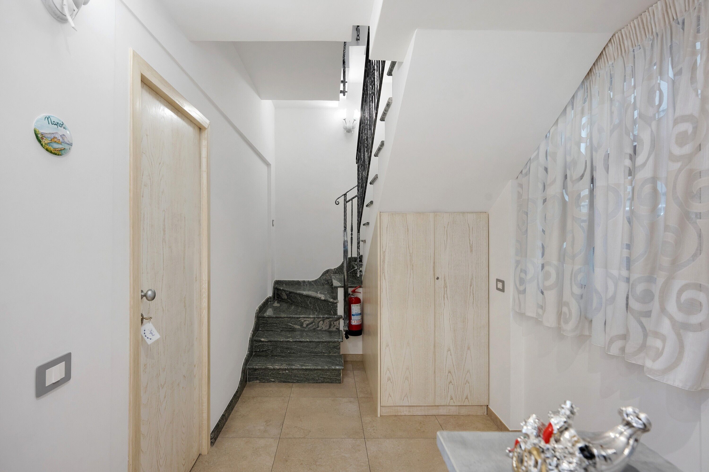 A hallway with a wooden door, a staircase, and a wall-mounted decorative item.