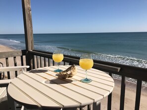 Ein Tisch mit zwei Gläsern Orangensaft auf einer Holzterrasse mit Blick auf den Ozean.