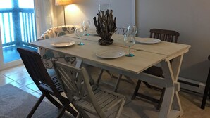Een eetgedeelte met een tafel voor vier personen, een aan de muur bevestigde televisie, en uitzicht buiten door een raam.