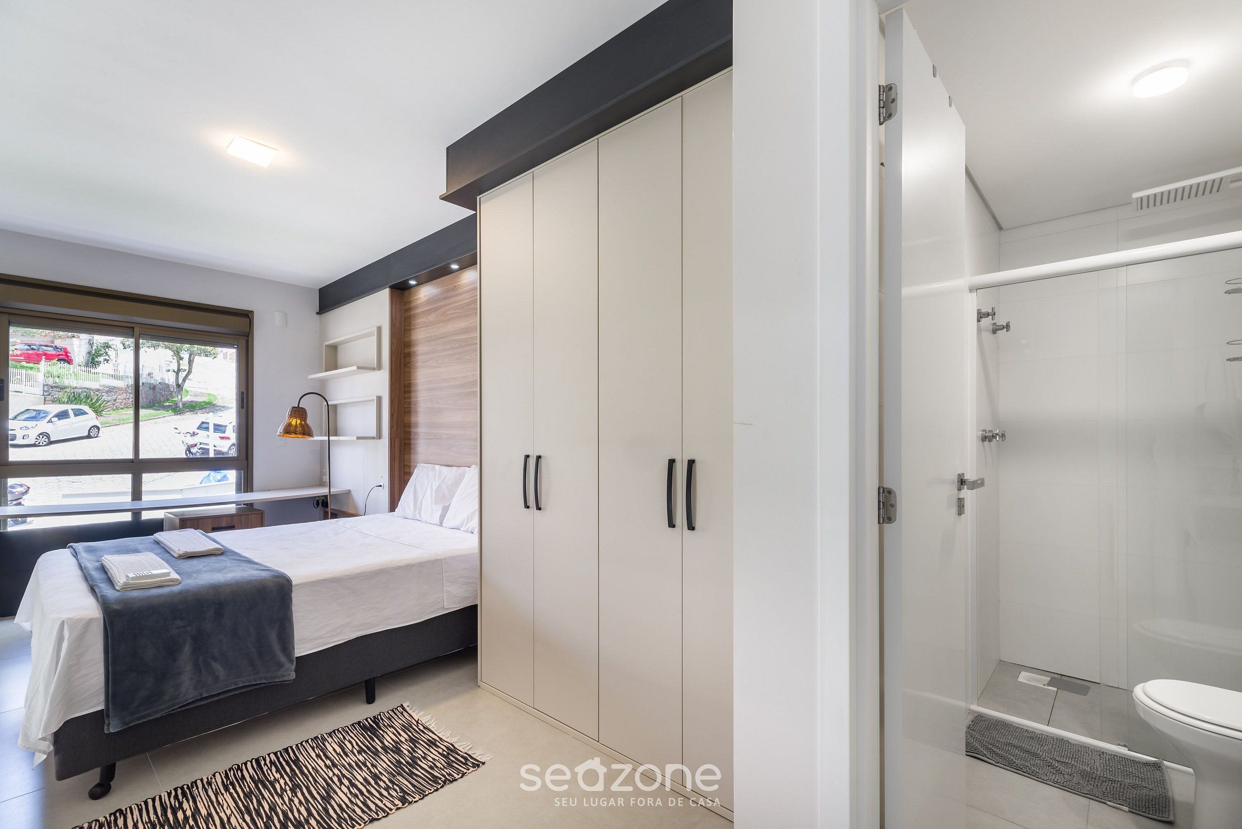 A modern bedroom with a bed, wardrobe, and a shower area.