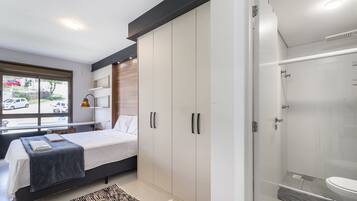 A modern bedroom with a bed, wardrobe, and a shower area.