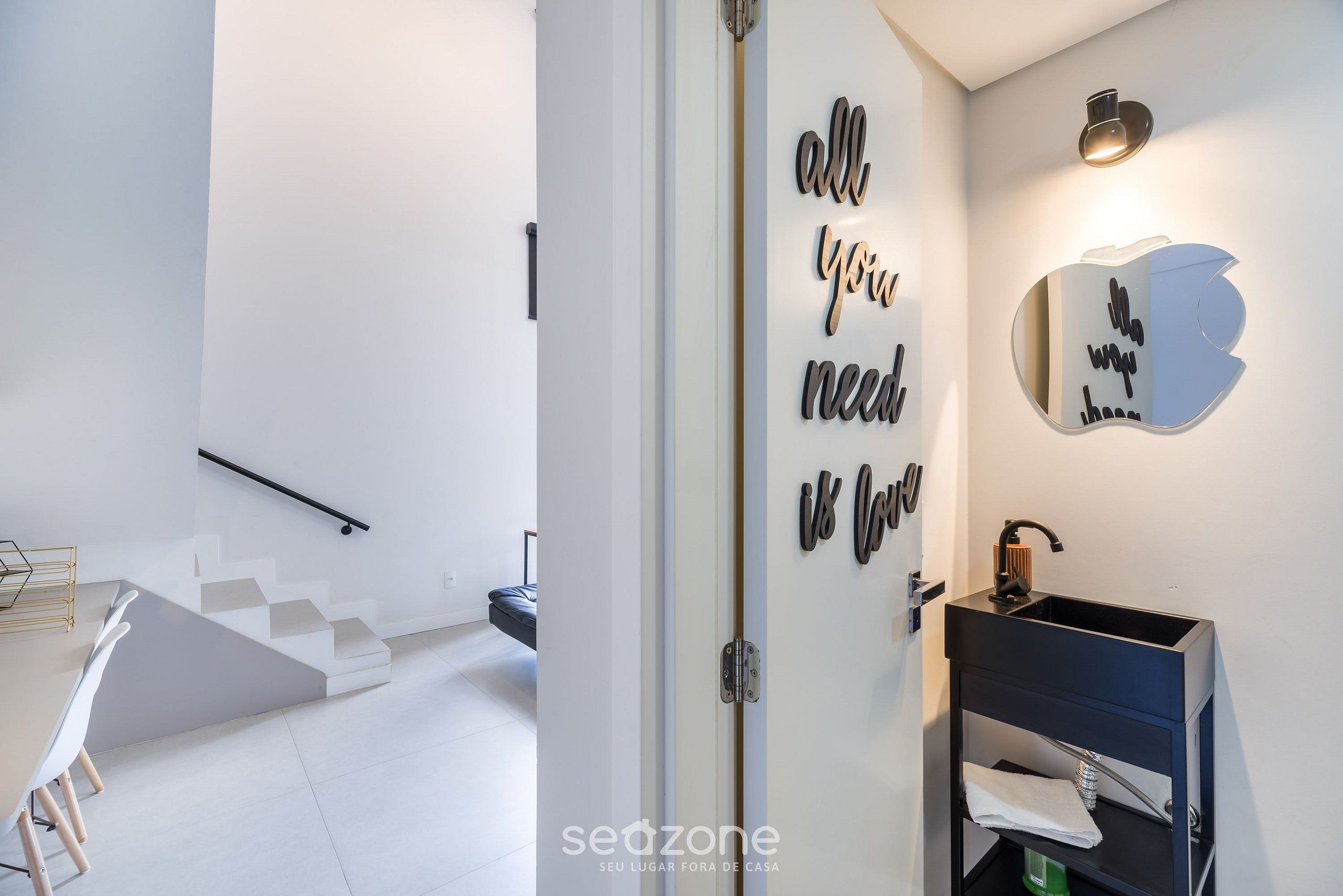 A modern bathroom with a black sink, a mirror, and motivational wall art.