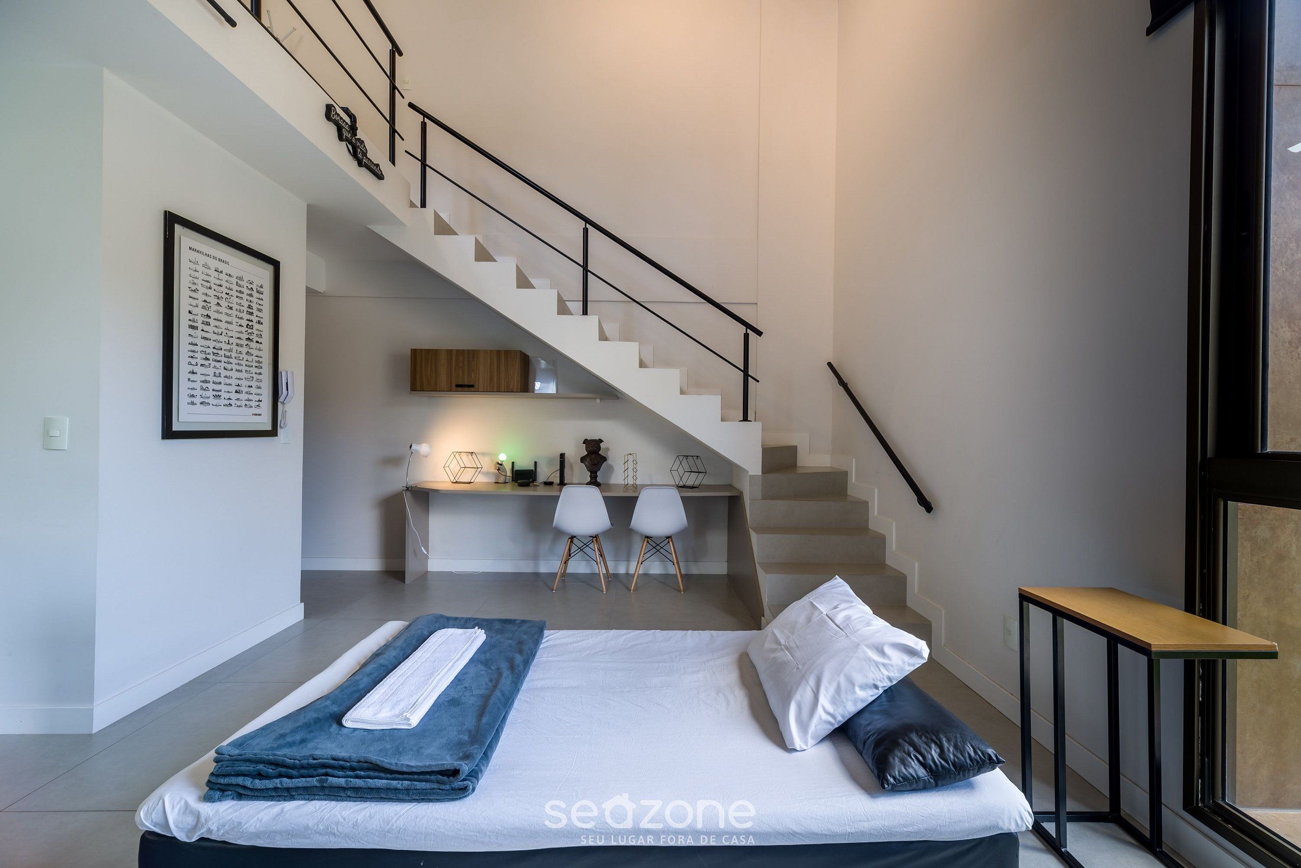 A bedroom with a bed, a desk, and a staircase.