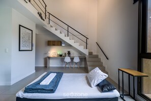 Una camera da letto con un letto, una scrivania e una scala.
