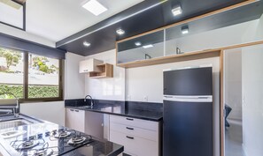 Una cocina moderna con estufa a gas, encimeras negras y armarios blancos.