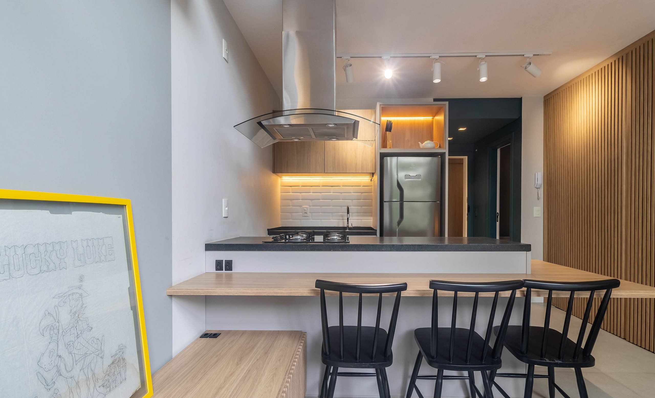 Una cocina moderna con una isla central, sillas negras y una obra de arte enmarcada en la pared.
