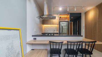 A modern kitchen with a central island, black chairs, and a framed artwork on the wall.