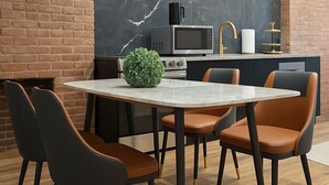 A modern kitchen with a marble backsplash, a brick wall, and a dining area with a round table and chairs.