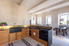 Eine Küche mit schwarzer Arbeitsplatte, Holzschränken, einem Spülbecken und einem Essbereich mit Tisch und Stühlen.