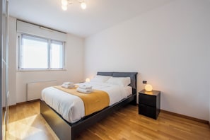Een moderne slaapkamer met een bed, nachtkastjes en een raam.