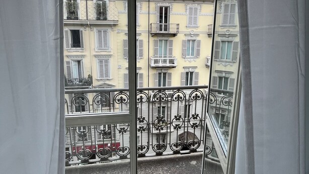 A balcony with a wrought iron railing, a view of a street with buildings, and a clear sky. - Fermata Marconi two-room apartment in the center of Turin (Torino)