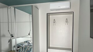 A modern bedroom with a bed, a wardrobe, a mirror, and a small bathroom area. - Fermata Marconi two-room apartment in the center of Turin (Torino)