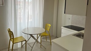 A compact kitchen with a round table and two yellow chairs, a white countertop, and a stainless steel sink. - Fermata Marconi two-room apartment in the center of Turin (Torino)