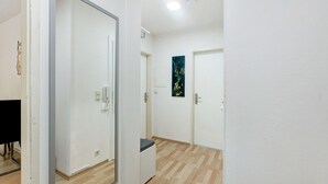 Un couloir aux murs blancs, doté d’un plancher en bois et de portes donnant sur différentes pièces.