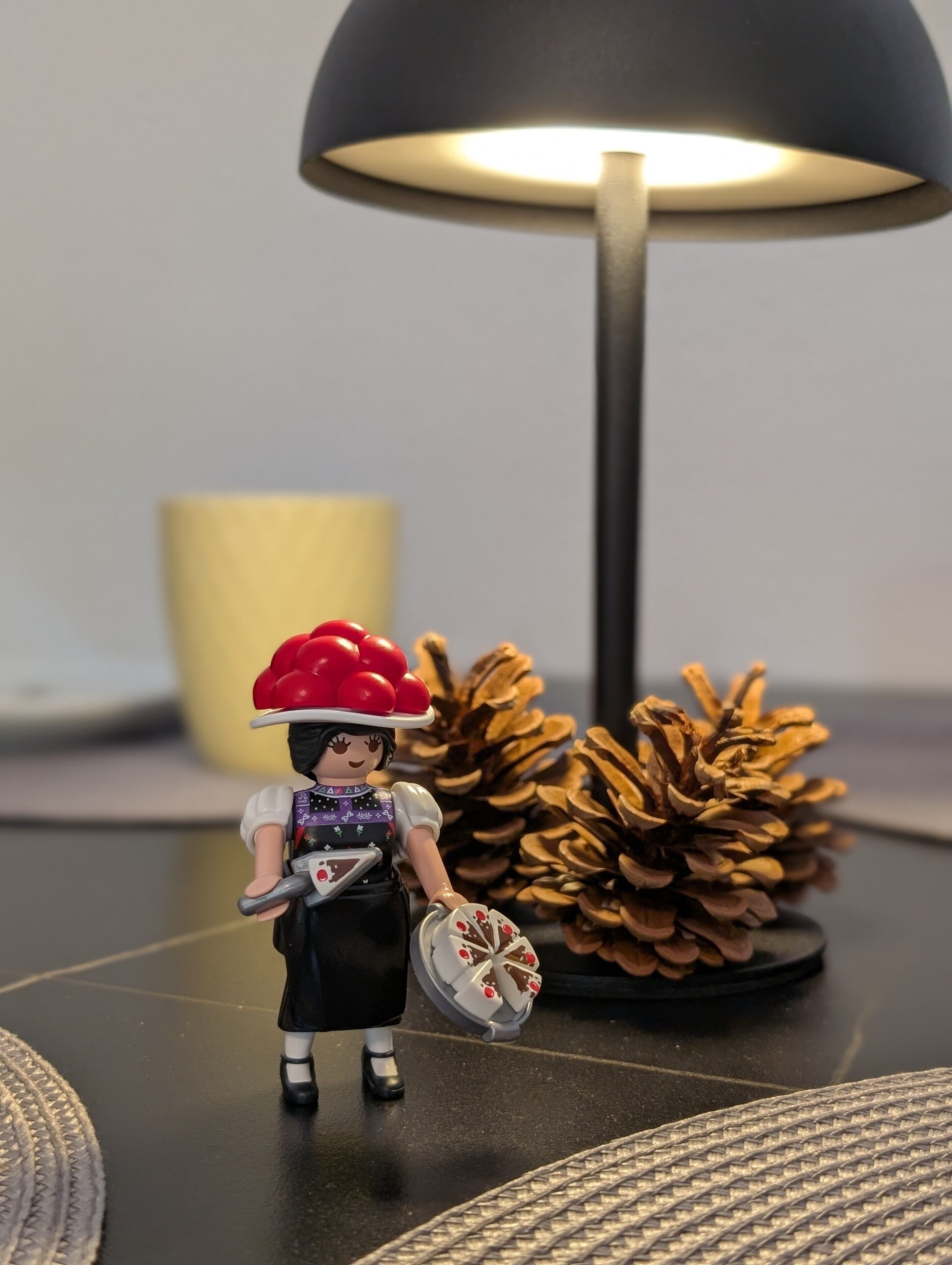 Een beeldje op een tafel met een lamp en dennenappels.