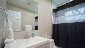 A bathroom with a white sink, mirror, and toilet. - Modern Beach Studio 3 (Pompano Beach)