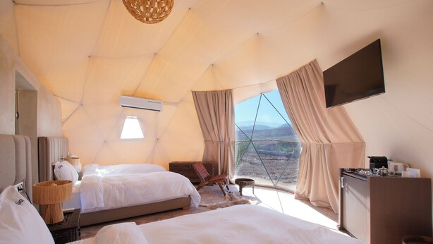 A tent-style room with two beds, a flat-screen TV, a desk, and a view of the landscape. - The Ranch Resort - Family Tent (Tahannaout)