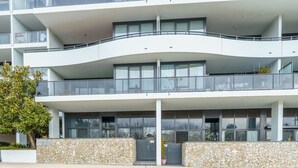 En moderne bygning med flere etager, altaner, store vinduer og en stenfassade.