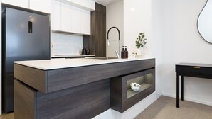Eine moderne Küche mit einem eingebauten Kühlschrank, einem Spülbecken mit einem Bogen-Wasserhahn und einer Arbeitsplatte mit Pflanze und Dekoration.