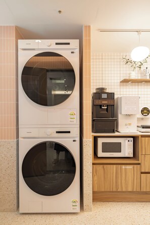 A laundry area with a Samsung washer and dryer, a coffee machine, and a microwave. - Slowon Hongdae (Seoul)