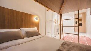 A modern hotel room with a large bed, wooden headboard, and a bright circular light fixture. - Slowon Hongdae (Seoul)