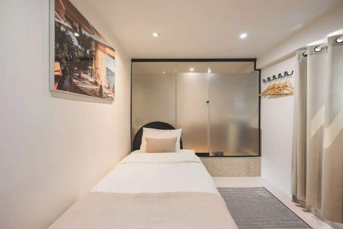 Una habitación de hotel moderna con cama, zona de ducha y vistas al exterior.