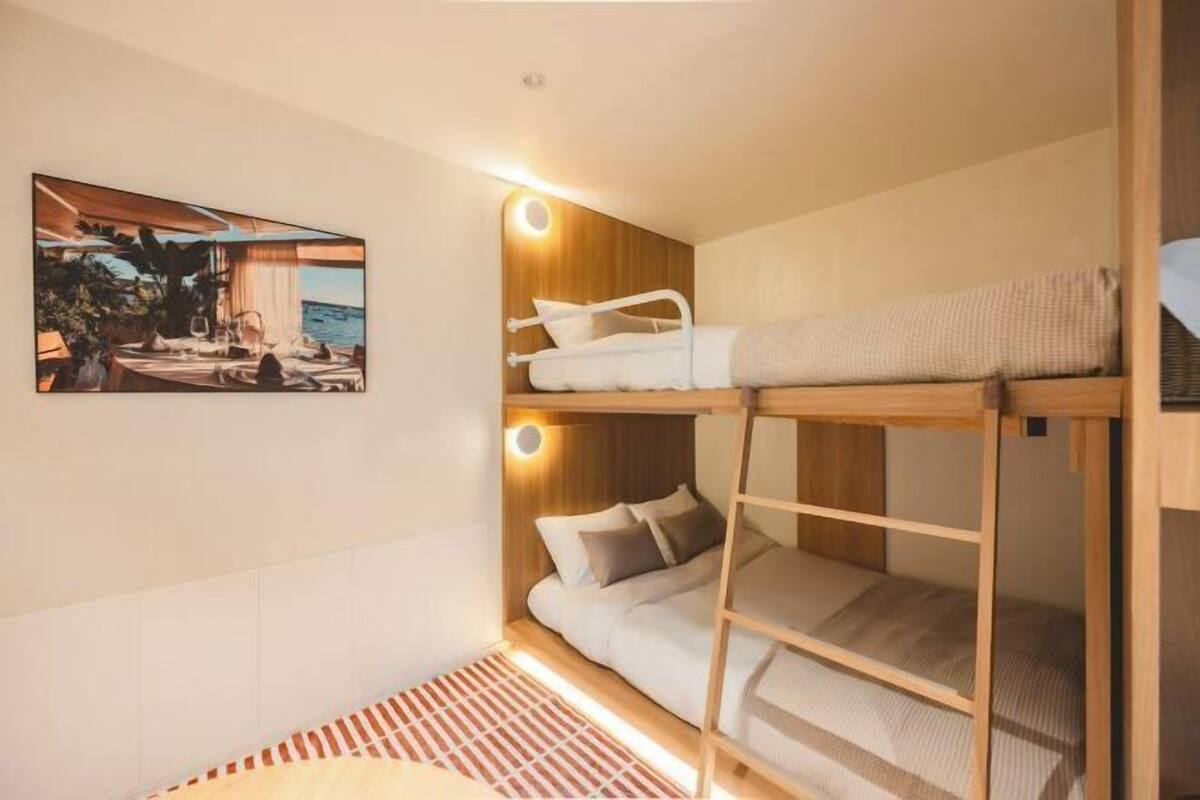 Habitación con literas, cabecera de madera, un cuadro en la pared y una alfombra a rayas en el suelo.