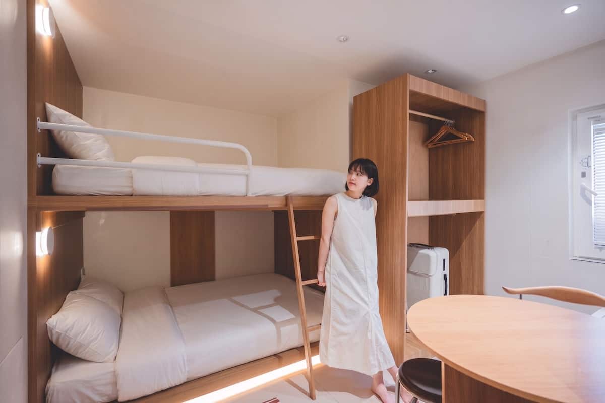 Habitación con literas, un armario de madera, una mesa y una silla.