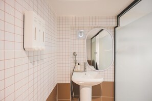 A bathroom with a white sink, a mirror, a handheld showerhead, and a soap dispenser. - Slowon Hongdae (Seoul)