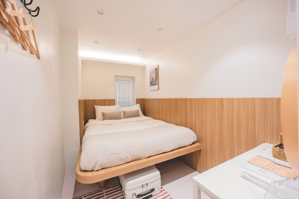 Un dormitorio con cama, escritorio y ventana.