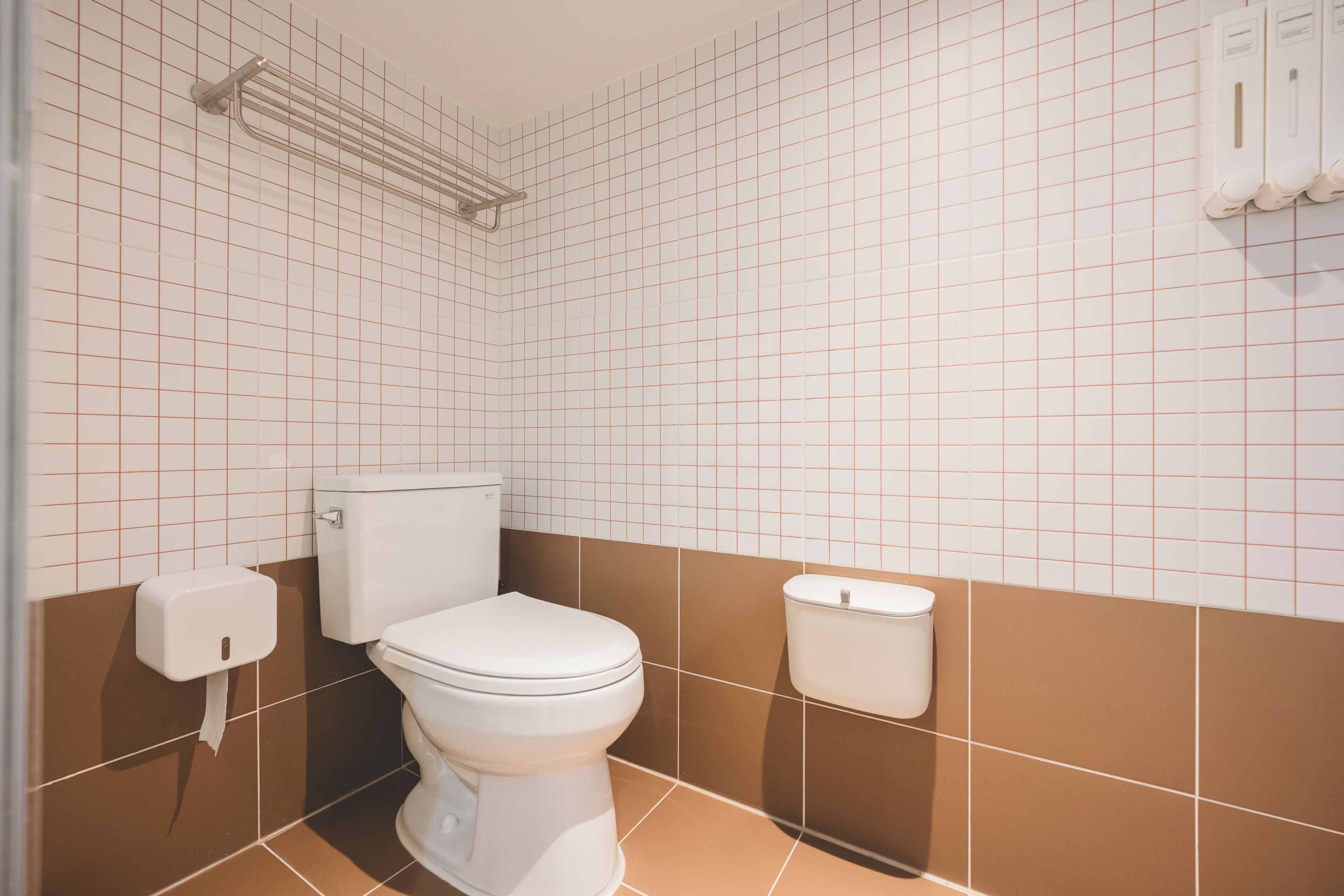 A bathroom with a toilet, a towel rack, and a hand dryer.