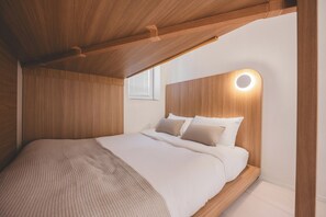 A bedroom with a wooden ceiling, a bed with white bedding, and a circular light fixture on the wall. - Slowon Hongdae (Seoul)