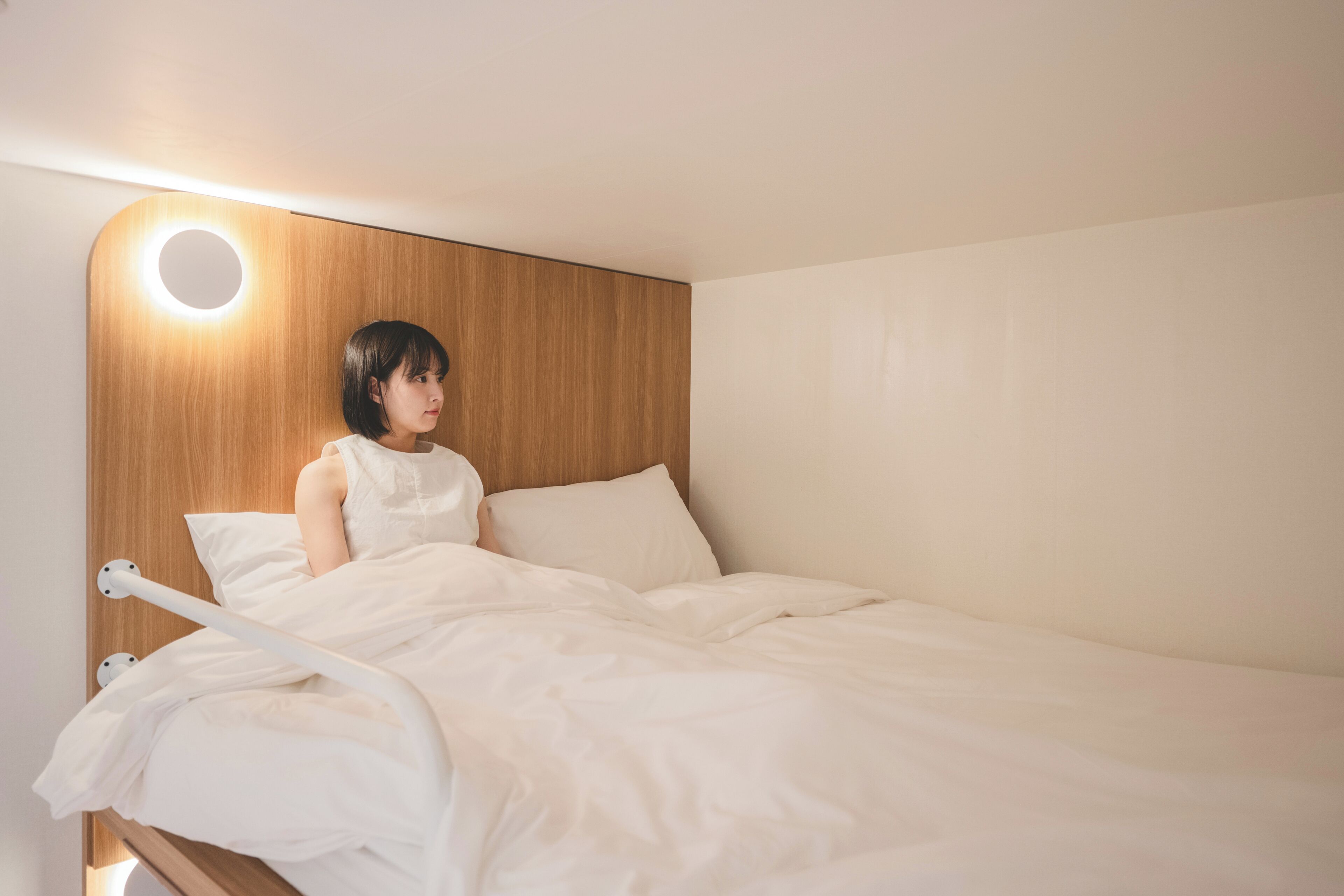 Una cama individual con cabecera de madera y lámpara de techo circular.