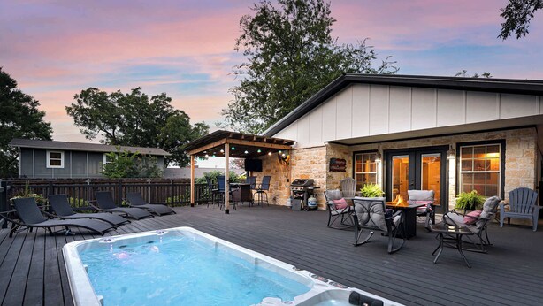 A deck with a hot tub, outdoor seating, and a barbecue area.