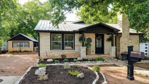 A stone house with a front porch, a mailbox, and a landscaped garden.