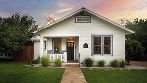A single-story house with a front porch, a small garden, and a stone pathway leading to the door.