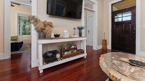 A living room with a mounted TV, a wooden coffee table, and a console table with decorative items.