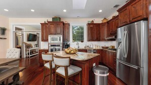 A modern kitchen with wooden cabinets, stainless steel appliances, and a central island with bar stools.