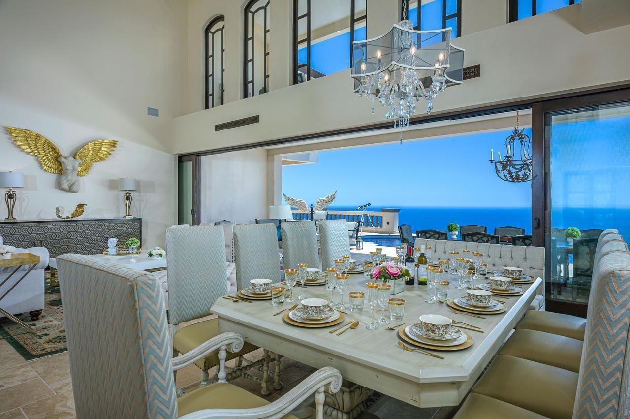 Un comedor con una mesa lista para seis personas, con vista a un paisaje marino.