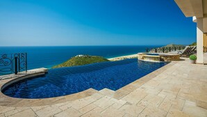 Una piscina infinita con vistas al océano y una pequeña isla.