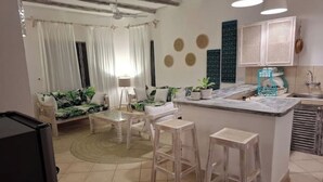 A modern kitchen with a central island, bar stools, and a dining area with a table and chairs. - Villa bonito (Mombasa)