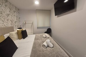 Une chambre d’hôtel avec un lit, deux serviettes, une télévision, une chaise et une fenêtre donnant sur un beau paysage.