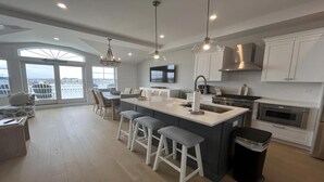 A modern kitchen with a large island, bar stools, a TV, and a view of the city. - Brand new Bayfront Luxury Townhome with Pool and Elevator. (Spray Beach)