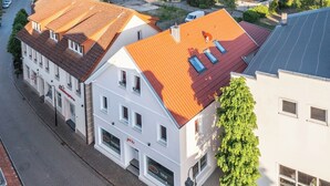 A multi-story building with a red-tiled roof, white walls, and multiple windows.